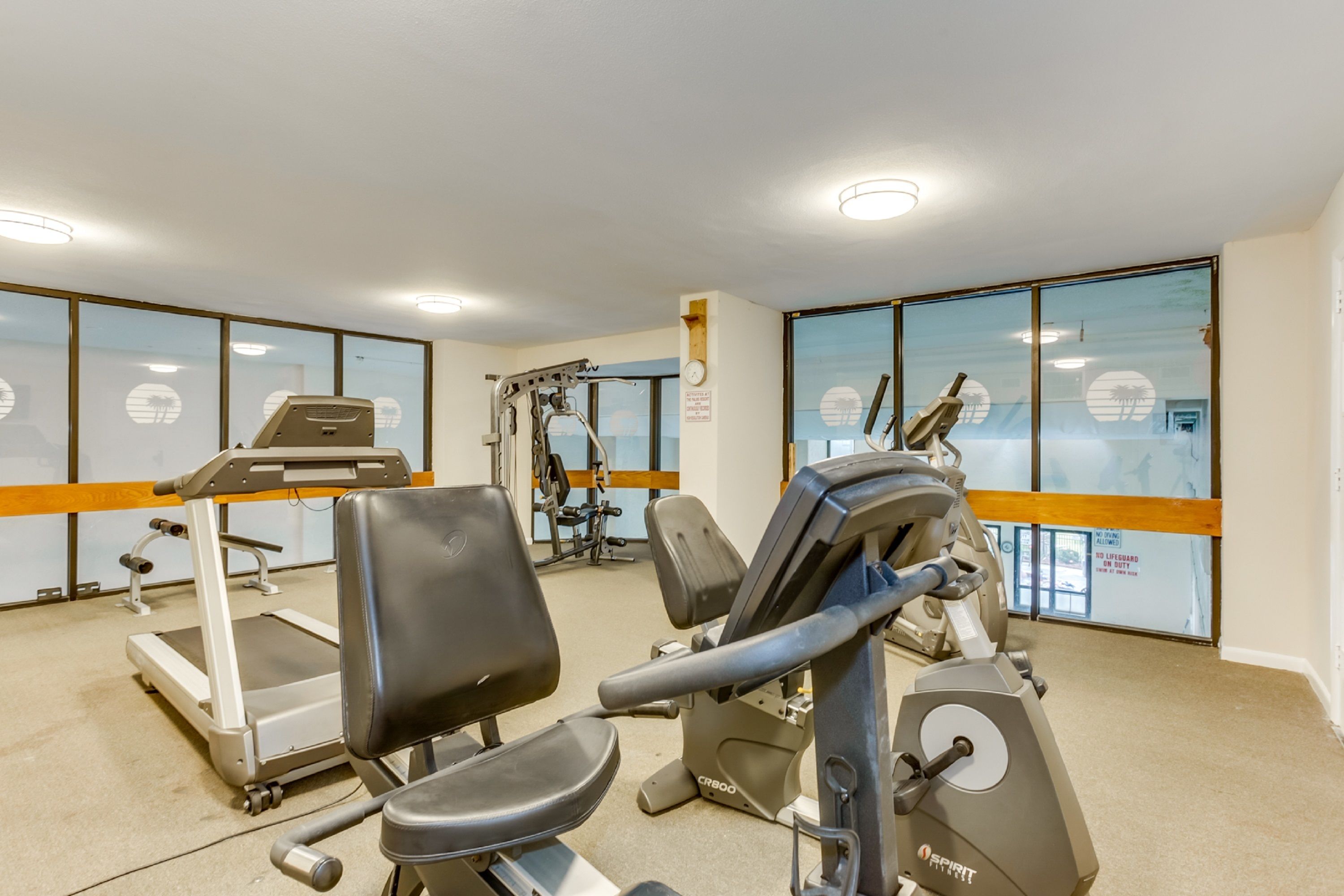 Un gimnasio con máquinas de cardio, máquinas de pesas y una caminadora.