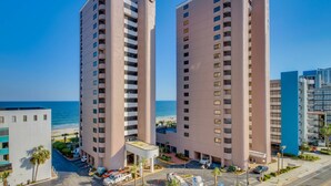 Un hôtel de grande hauteur, avec de nombreux étages, une piscine sur le toit et une vue sur la plage.