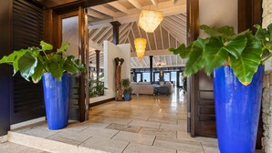Un hall d’entrée spacieux avec un plafond haut, de grands jardinières bleues et un lustre.