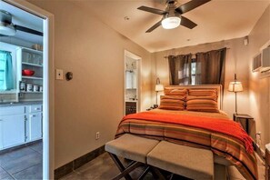Une chambre à coucher avec un lit, des lampes de chevet, un ventilateur de plafond et une vue sur la salle de bain.