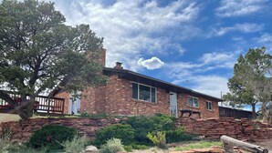 A brick house with a stone retaining wall, surrounded by trees and greenery. - Rustic isolation near Capitol Reef National Park (Teasdale)