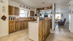 Una cucina con mobili in legno, un frigorifero bianco e un'area pranzo con una sedia e un tavolo.