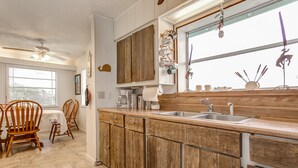 Una cucina con mobili in legno, un lavello e una zona pranzo con sedie e tavolo.