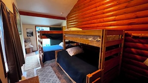 A cabin with bunk beds, a small table, and a patterned rug.