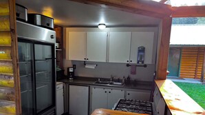 Une cuisine de taille réduite équipée d’un réfrigérateur, d’une cuisinière et de placards.