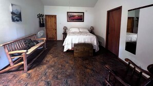 Une chambre à coucher comprenant un lit, un banc en bois, une table de chevet et un ventilateur de plafond.