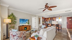 A spacious living area with a sofa, a coffee table, a TV, and a ceiling fan.