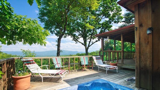 A wooden deck with a hot tub, lounge chairs, and potted plants.