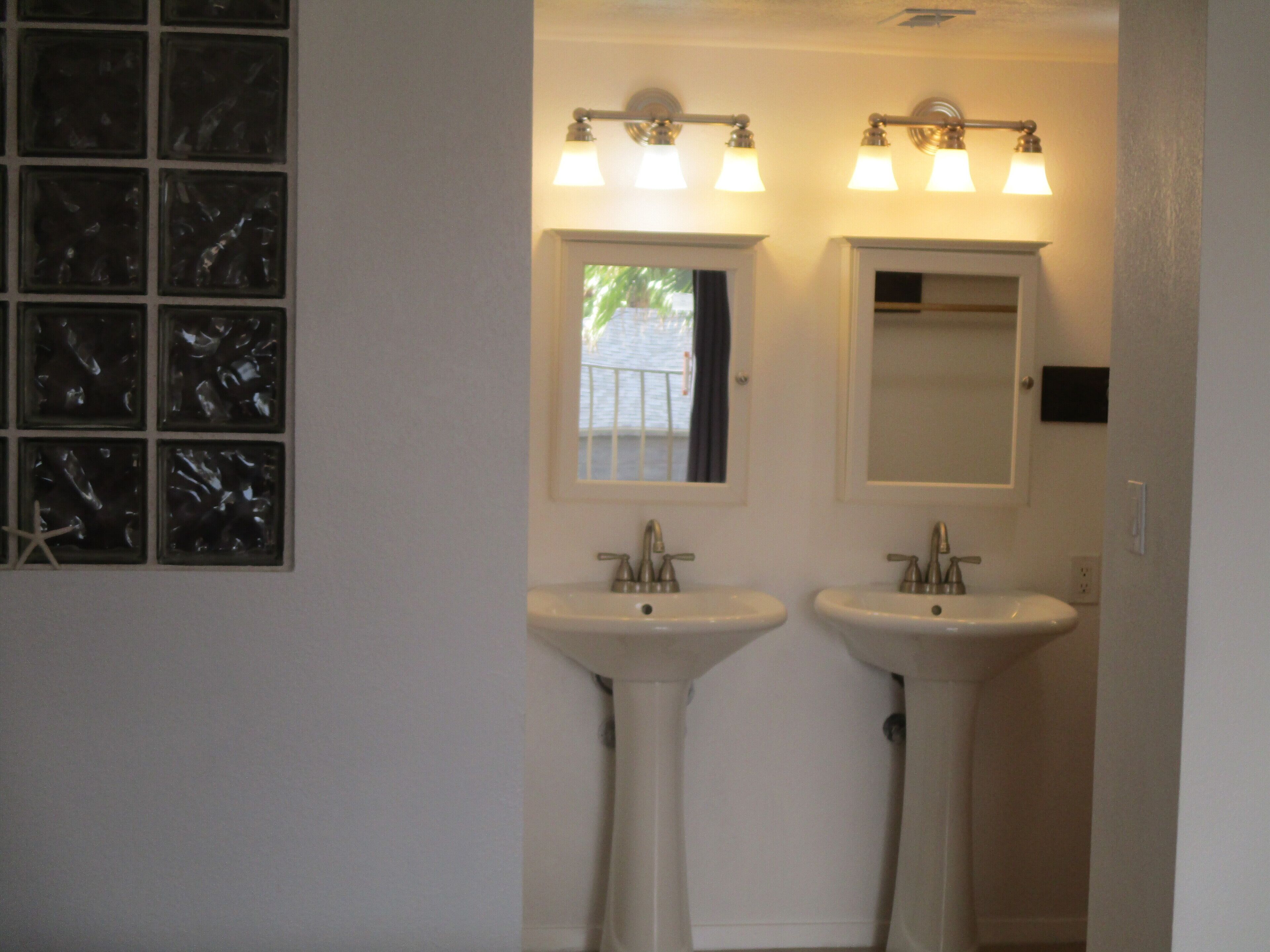 Une salle de bain avec deux lavabos, une fenêtre offrant une belle vue et un miroir au-dessus de chaque lavabo.