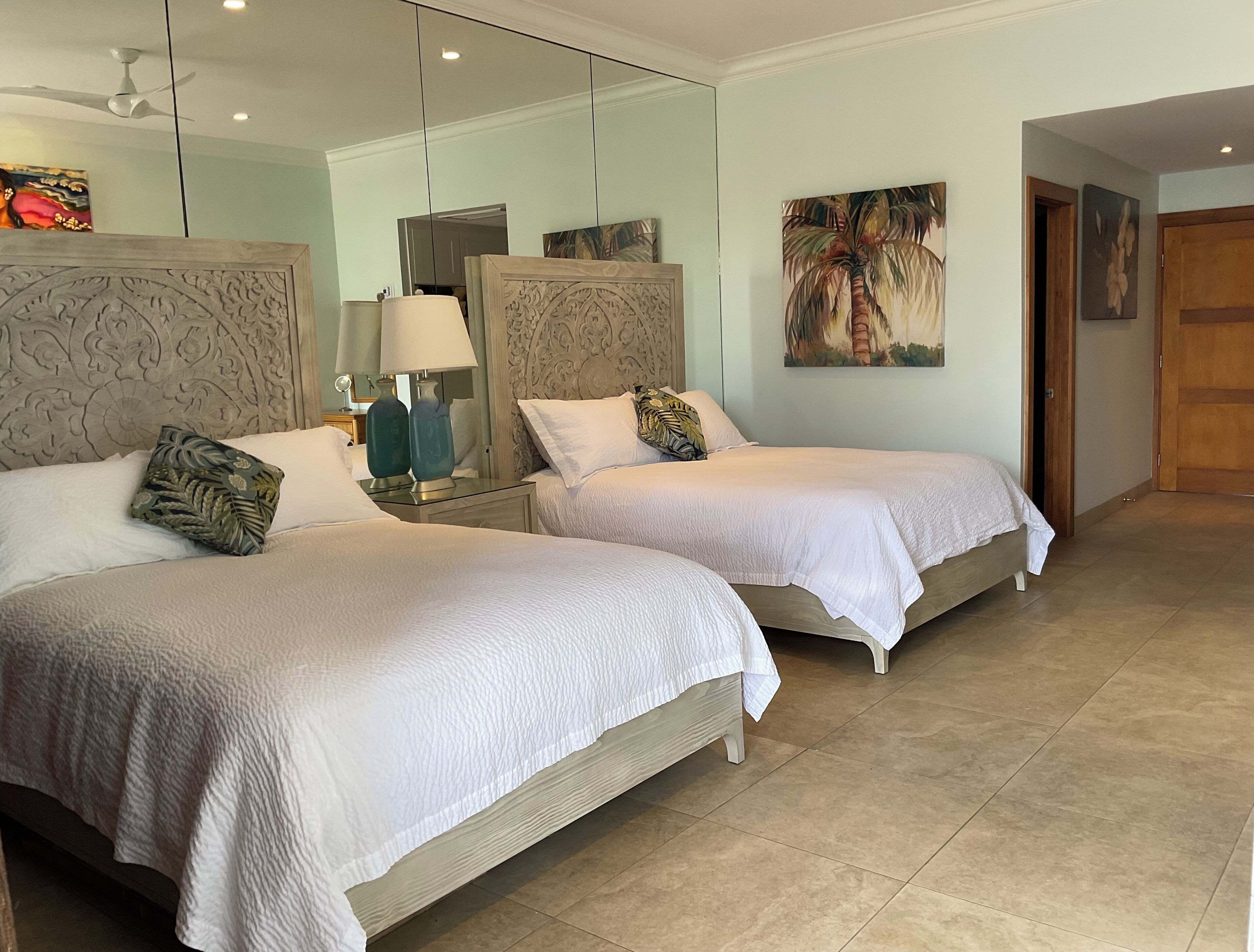 Ein Hotelzimmer mit zwei Betten, einem großen Spiegel und Bildern an den Wänden.
