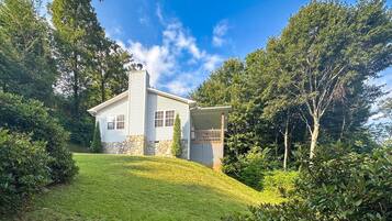 A two-story house with a stone foundation, a chimney, and a small porch.