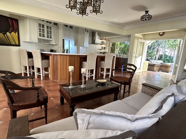 A spacious living area with a sofa, chairs, a coffee table, and a kitchen in the background. - On The Beach Luxury Mediterranean Villa . Gated Community Partial or full staff (Cabarete)