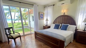 Une chambre avec un grand lit, un ventilateur de plafond, une table de chevet, une chaise et une vue sur l’extérieur.