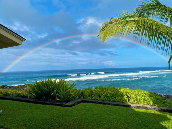 A coastal view with a clear sky, ocean waves, and a rainbow.