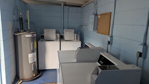 A laundry room with industrial-style washers and dryers, pipes, and a control panel. - Pet Friendly Longboat Key Condo with View of Gulf  (Longboat Key)