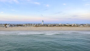 Un hotel frente al mar con vistas a la costa, una torre de agua destacada y una playa arenosa.