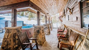 Une cabane en bois avec des piliers en pierre, des bancs en bois et un jacuzzi.