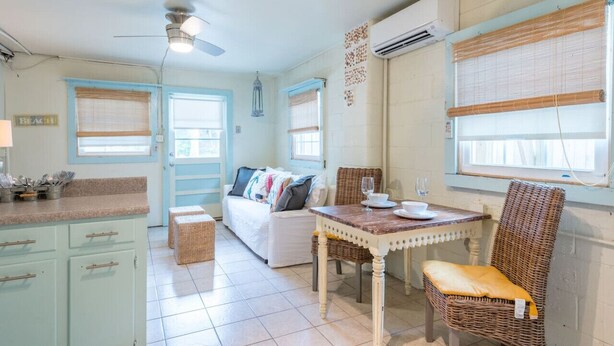 A kitchen with a dining table, wicker chairs, and a white sofa.