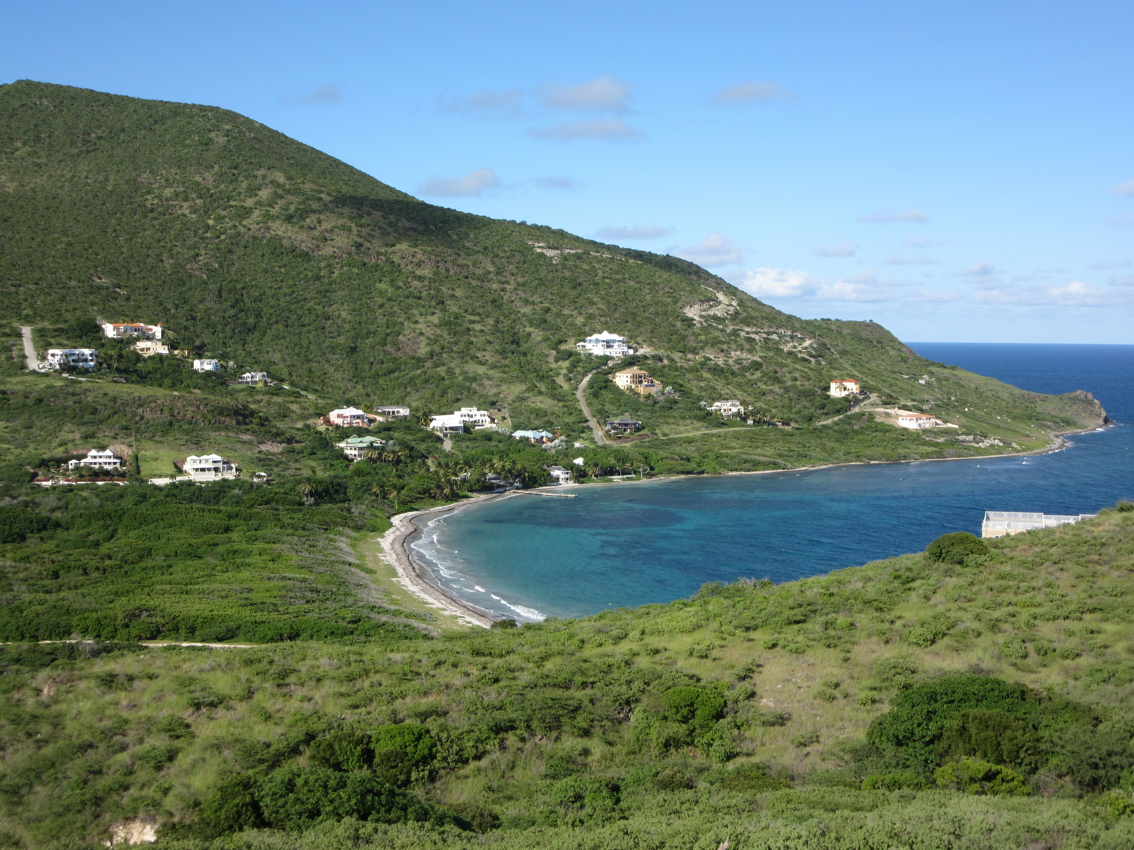 A coastal area with houses on a hillside overlooking the ocean.