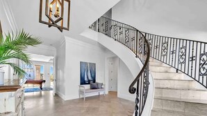 A spacious living area with a curved staircase, a pool table, and a bench. - Over the Top | 7 Bedroom! | Clubhouse Amenities! Pickleball, Gym & Hot Tub! | Pet-Friendly Escape in Destin | Private Pool | Gulf Views! Wedding Friendly! (Destin)