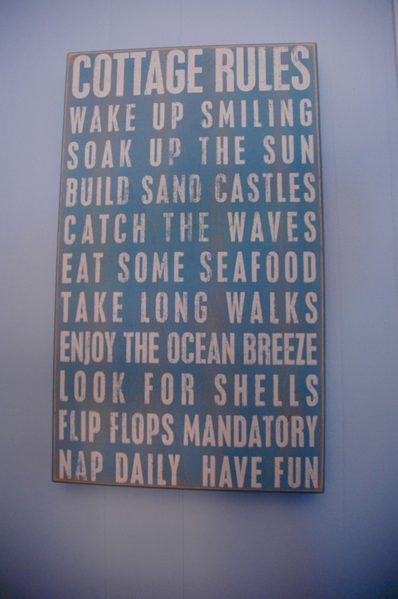A sign listing 'Cottage Rules' with activities like 'Wake up smiling,' 'Soak up the sun,' and 'Eat some seafood.'