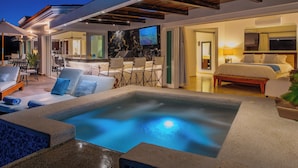 Un espacio exterior moderno con un jacuzzi, sillones reclinables y zona de comedor.
