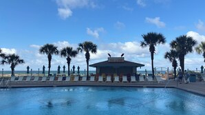A pool area with lounge chairs and umbrellas, a tiki bar, and a view of the beach. - RIGHT ON THE BEACH! First Floor! Walk out slidingdoor  your steps from the beach (Panama City Beach)