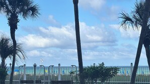A park with palm trees, a pathway, and a view of the ocean. - RIGHT ON THE BEACH! First Floor! Walk out slidingdoor  your steps from the beach (Panama City Beach)