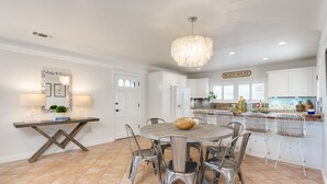 Cozinha moderna com armários brancos, uma mesa de jantar redonda e um candelabro.