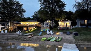 Una proprietà sul lago con molo, sedie da spiaggia, kayak e un portico coperto.