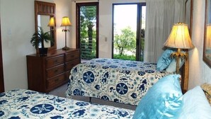 A bedroom with two beds, a dresser, a ceiling fan, and a window with a view of greenery. - Ocean View Poipu Beach Condo (A/C) 804 (Poipu Beach, Koloa)
