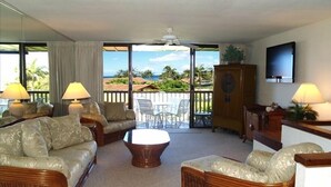 A living room with wicker furniture, a television, and a view of the outdoors. - Ocean View Poipu Beach Condo (A/C) 804 (Poipu Beach, Koloa)