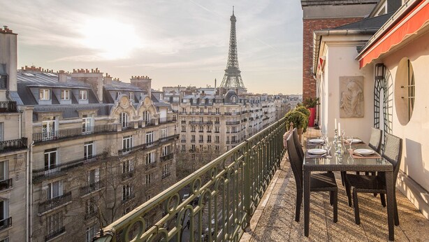 A balcony with a table set for dining, overlooking a cityscape with the Eiffel Tower in the distance. - One-of-a-Kind 3-bedroom OMG Eiffel Views & Wraparound Terrace (Paris)