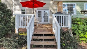 A wooden deck with a red umbrella, white railings, and a sign that reads "Car Real." - Charming home, perfect for families, Bikers,  Brevard College, College,  camps  (Brevard)