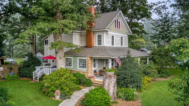 A two-story house with a porch, a chimney, and a well-maintained garden. - Charming home, perfect for families, Bikers,  Brevard College, College,  camps  (Brevard)