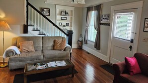 A living room with a sofa, coffee table, and a staircase. - Charming home, perfect for families, Bikers,  Brevard College, College,  camps  (Brevard)