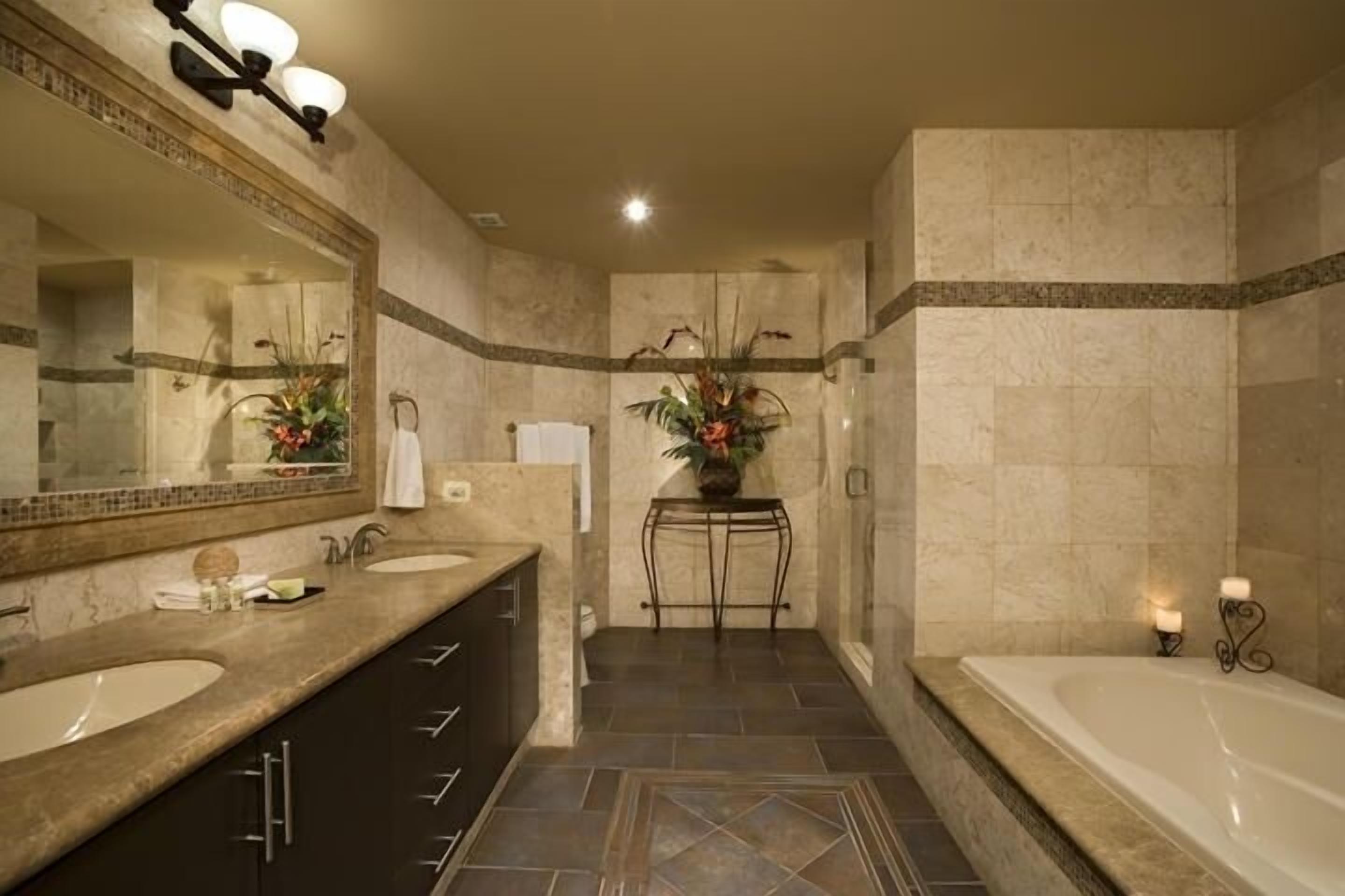 A modern bathroom with two sinks, a large bathtub, and a shower area.