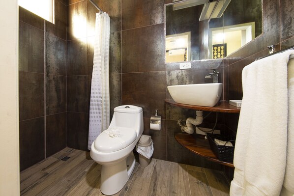 A modern bathroom with a toilet, sink, and mirror. - 4 BR/4 BA, Pool, Ocean View, Steps from the Beach, Reduced Rates (Playa Potrero)