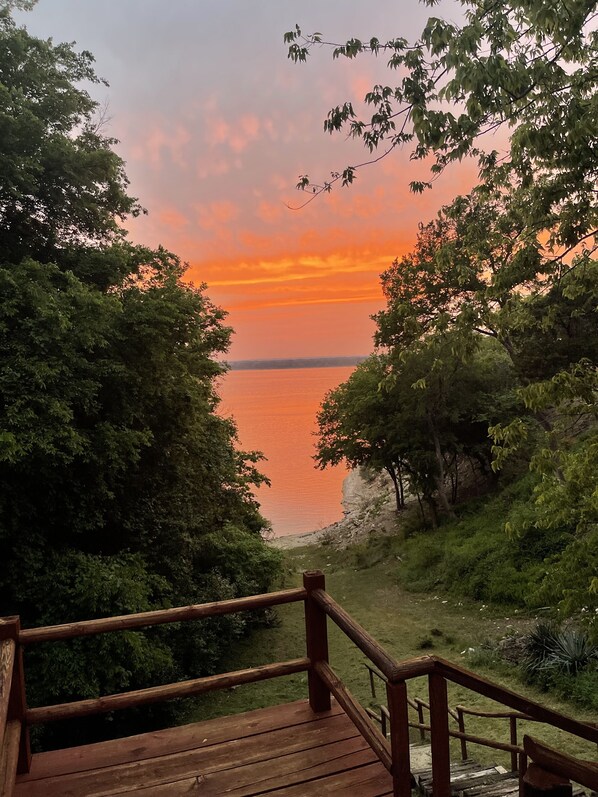 A wooden deck overlooking a body of water with a sunset.