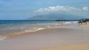 Ein Strand mit badenden und spazierenden Personen.