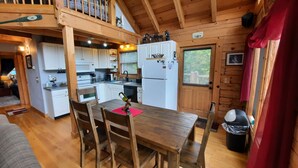A cozy cabin-style kitchen with wooden walls and a dining area.