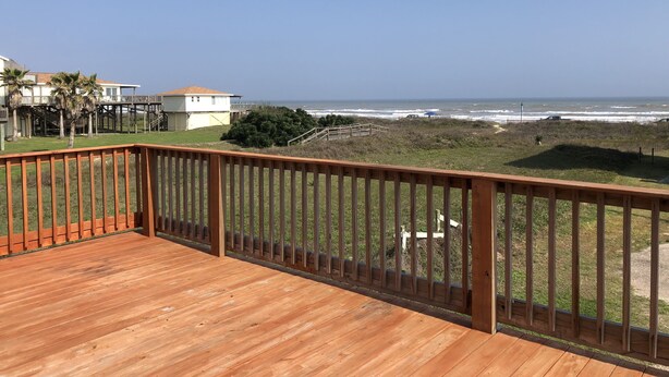 Um deck de madeira com vista para o oceano e uma casa com varanda.