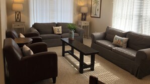Uma sala de estar com dois sofás, uma mesa de centro e uma mesa lateral com luminárias.
