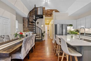 Une cuisine moderne dotée d’un îlot central, d’un escalier en colimaçon et d’un coin repas avec des chaises à motifs.