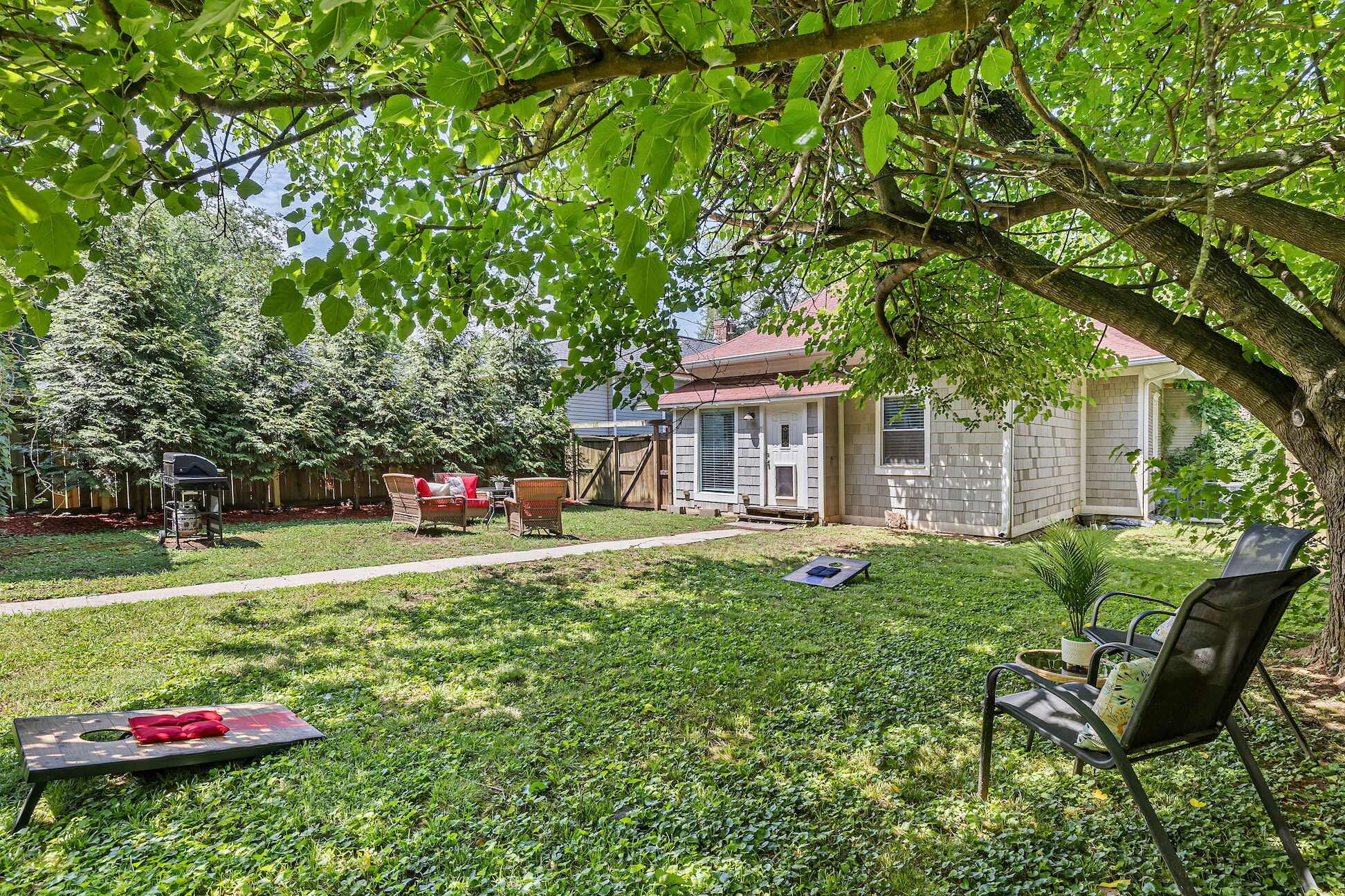A backyard with a barbecue grill, a covered patio area, and a lawn.