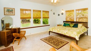 A bedroom with a bed, desk, chair, and large windows with blinds. - Affordable Luxury on Kaloli Point.  (Keaau)