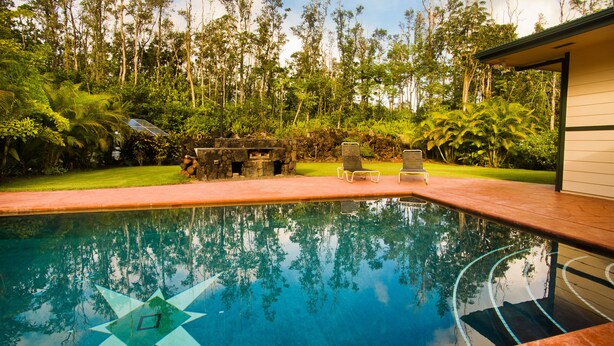 A swimming pool with a star design, surrounded by lush greenery and two lounge chairs. - Affordable Luxury on Kaloli Point.  (Keaau)