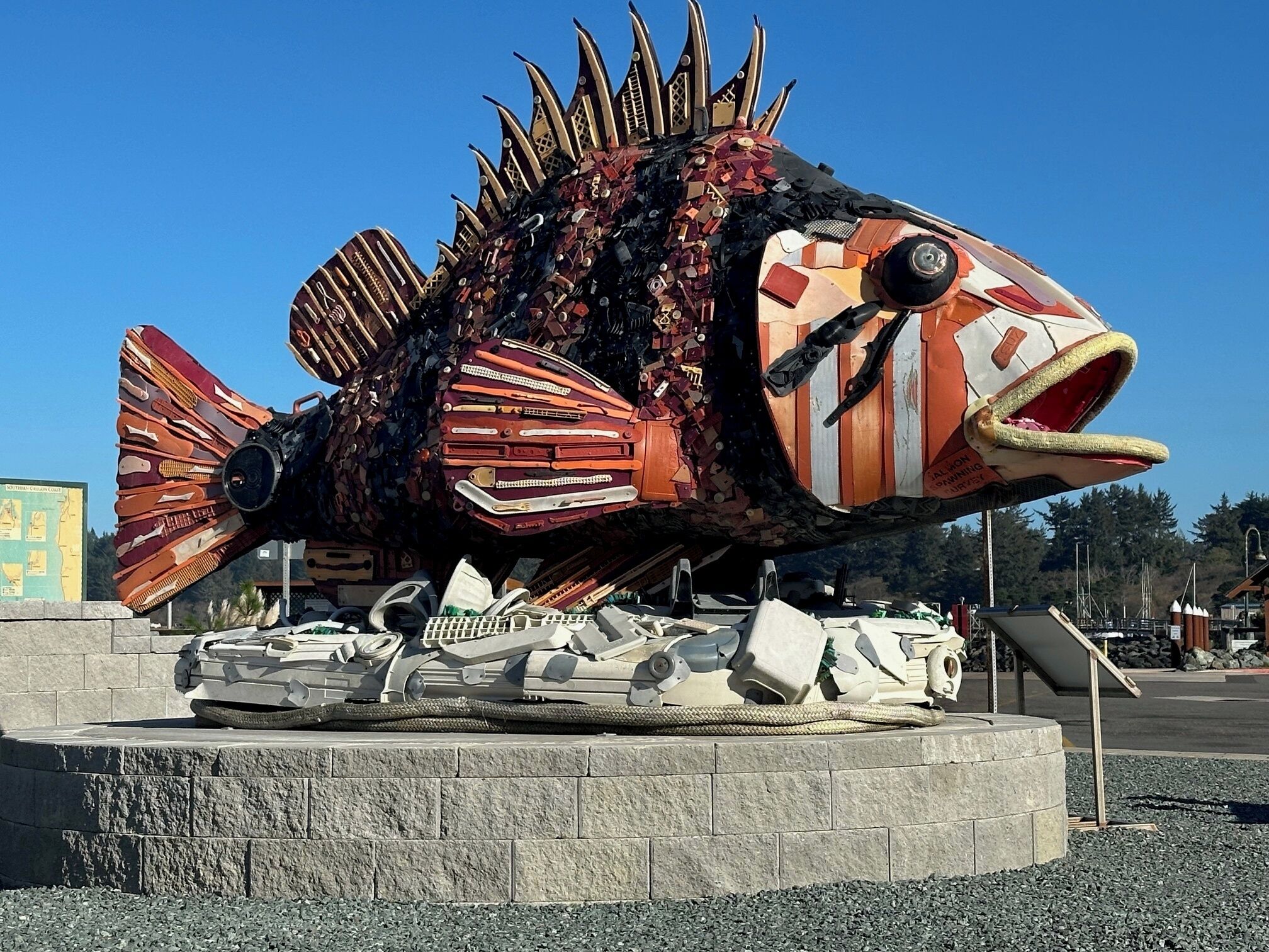 A large, colorful fish sculpture with mechanical parts and a sign that reads "ALLEYON PARKING".