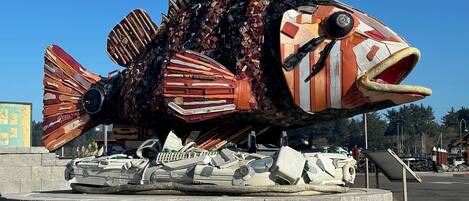 A large, colorful fish sculpture with mechanical parts and a sign that reads "ALLEYON PARKING".