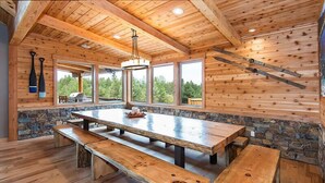 A rustic wooden interior with a large stone wall, wooden benches, and a stone fireplace.